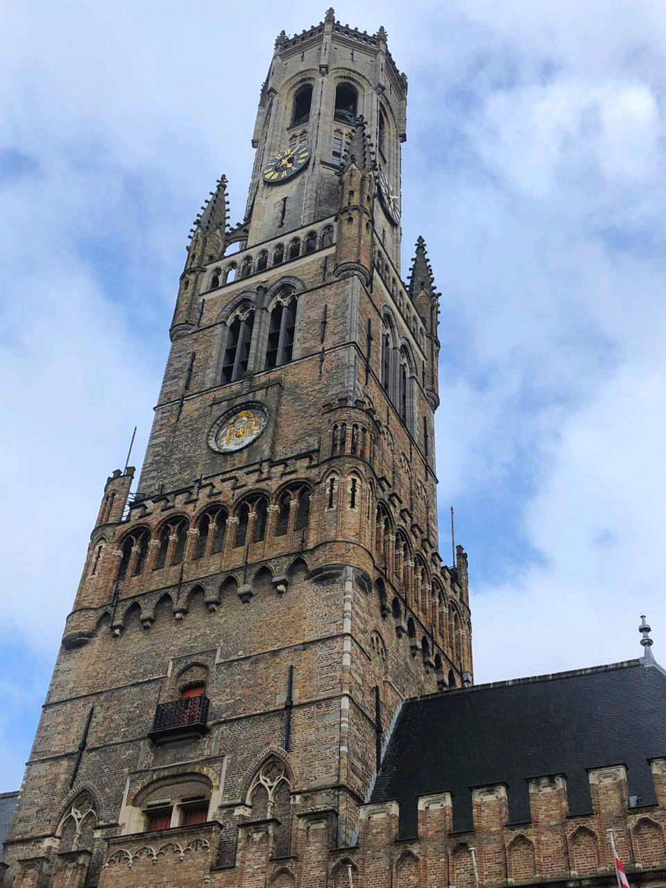The belfry of Bruges towers impressively upto the sky while musicians play under its vaulted arches.